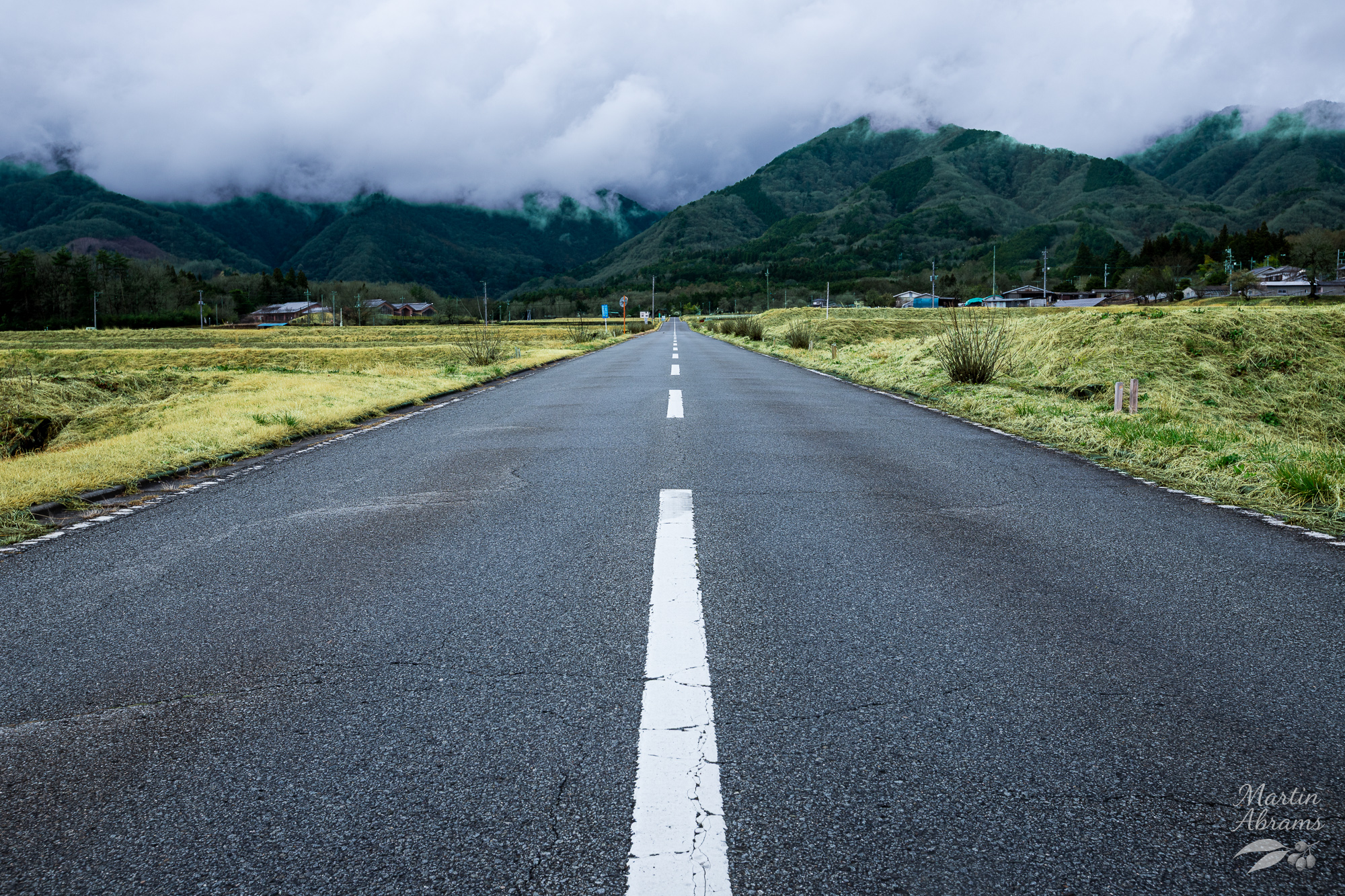 Road going into the mountain with thick cloud